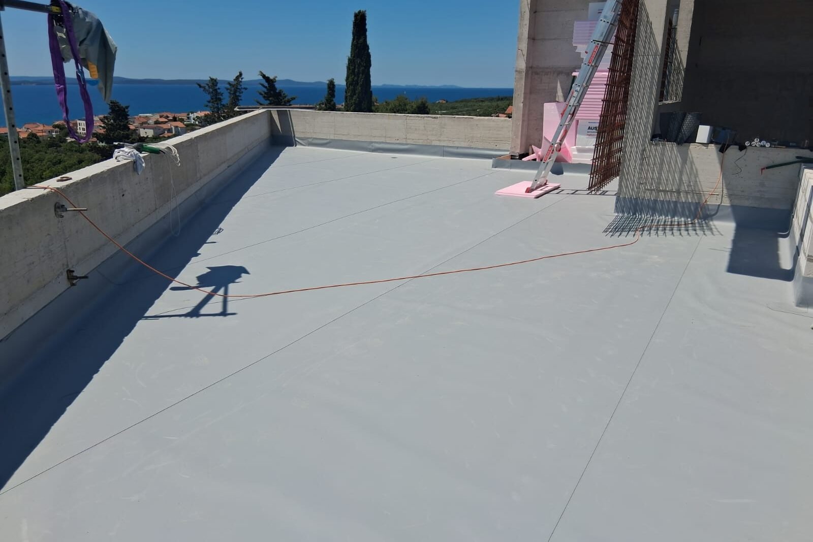 Ravni krov prekriven sivom membranom uz otvoreni pogled prema moru